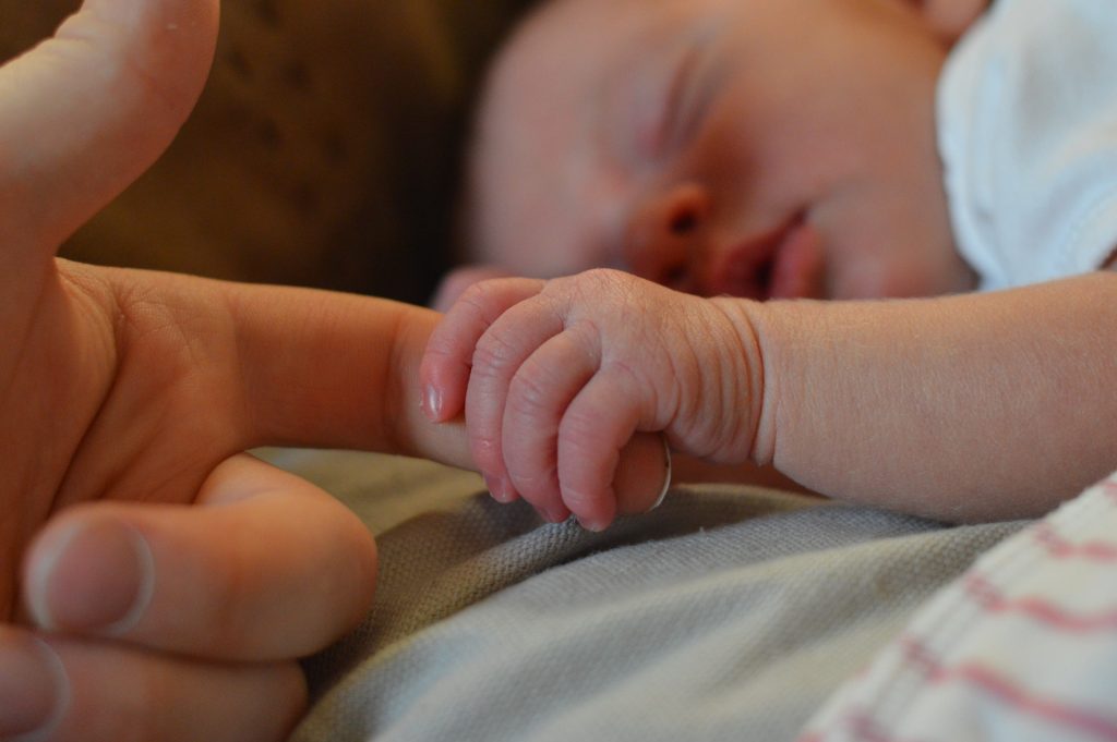 a new baby holding the finger of a parent