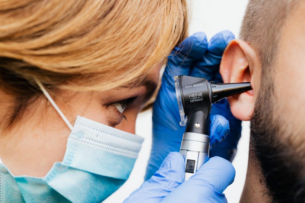 An audiologist inspects an ear to see if earwax removal is required