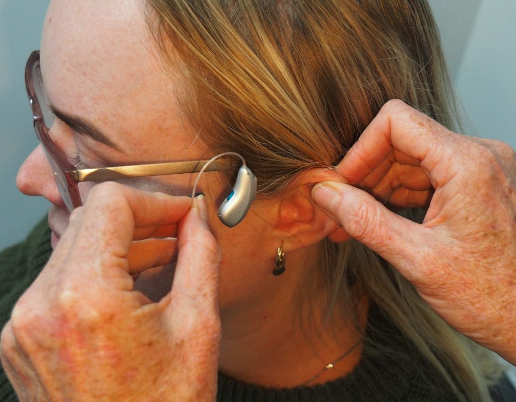 audiologist applying hearing aid to patient
