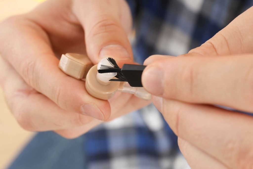 multifunctional tool being used to clean a hearing aid 