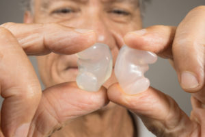 an older man holding two custom ear moulds