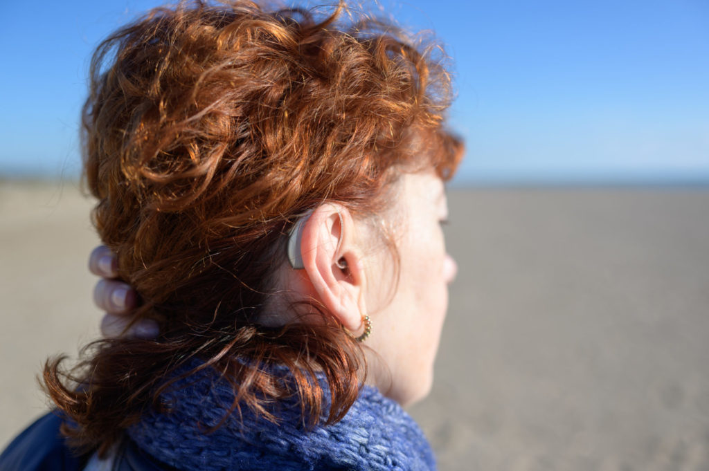Young woman wearing a hearing aid at the beach